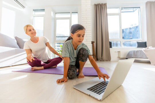 Mother And Daughter Make Yoga Exercise Online With Laptop At Home