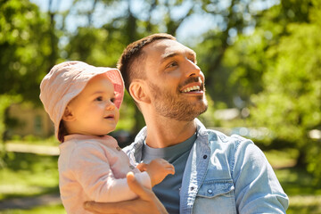 family, fatherhood and people concept - happy father with baby daughter at summer park