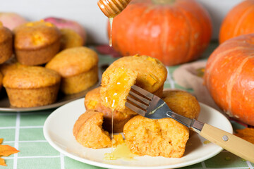 autumn pumpkin cupcakes with fresh pumpkin for thanksgiving day. autumn composition of pumpkin and maple leaves with baked muffins. cupcake pieces pour honey