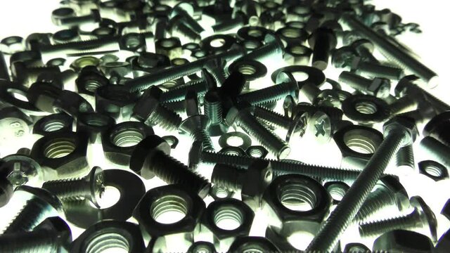 Video showing insulated bolts, nuts and washers passing through in backlight. Galvanized metal fasteners.