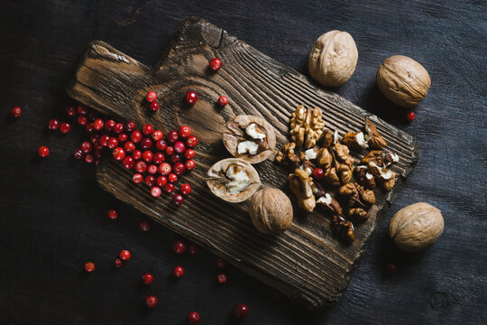 Walnuts with lingonberry on cutting board on table top  view