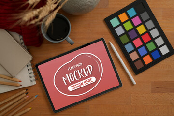Designer workspace with mock up tablet, colour checker, painting tools and decorations