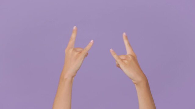 Close up cropped woman hands depicting heavy metal rock sign horns up gesture fooling rock-n-roll isolated on pastel purple violet background in studio. Copy space advertising area workspace mock up