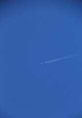 飛行機雲を描きながら青空を飛ぶ飛行機