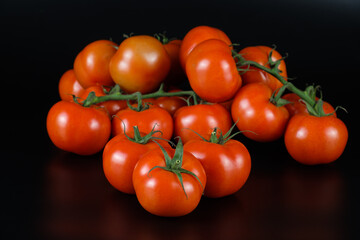 Eine große Mengem ein Haufen frischer saftiger rote Tomaten / Rispentomaten auf einem schwarzen Hintergrund