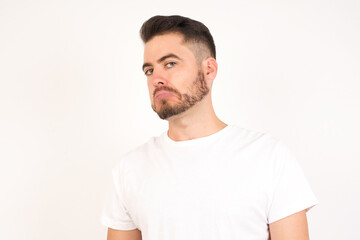 Fototapeta premium Beautiful man with snobbish expression curving lips and raising eyebrows, looking with doubtful and skeptical expression, suspect and doubt. Standing indoors over gray background.