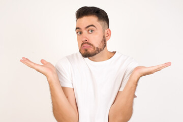 Puzzled and clueless young man with arms out, shrugging his shoulders, saying: who cares, so what, I don't know. Negative human emotions, facial expressions, life perception and attitude.