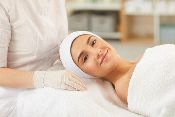 Obraz na płótnie Canvas Smiling young woman looking at camera after procedure of facial massage