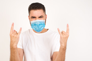 Born to rock this world. Joyful man in fashionable clothes screaming out loud and showing with raised arms horns or rock gesture, expressing excitement of being on concert of band.