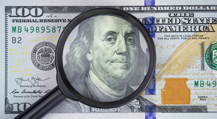 Magnifying glass on one hundred dollar bill, business concept