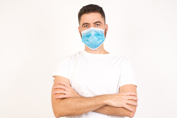 Waist up portrait of young handsome caucasian male with positive expression, has crossed arms, feels happy and confident, wears casual clothes, isolated over gray background.