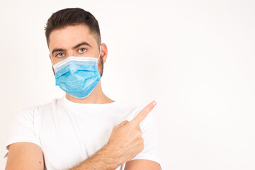 Excited surprised fashionable boy points happily aside on copy space of gray background for your fashion clothing advertising information or promotional text.