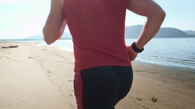Man runs on a beach. Young sportive man runs barefoot on a sandy coast along the river