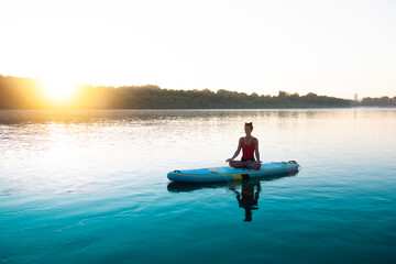 Woman meditating and practising yoga during sunrise