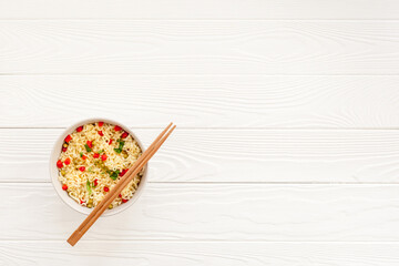 Instant noodle with pepper,peas and greens. White wooden background top view copy space
