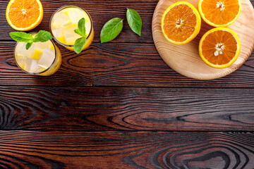 Refreshing orange juice with ice on dark wooden background top view flat lay copy space