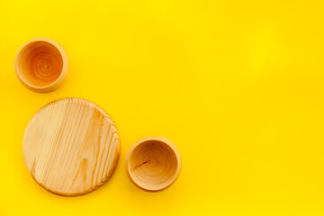 Obraz na płótnie Canvas Set of rustic wooden tableware - bowls and utensils on yellow background top view