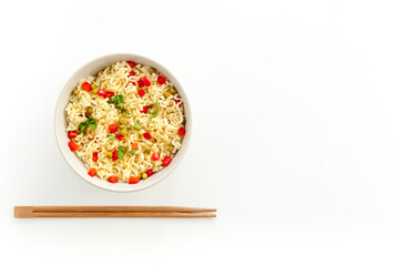 Instant noodle with pepper,peas, chopstick and greens. White background top view copy space