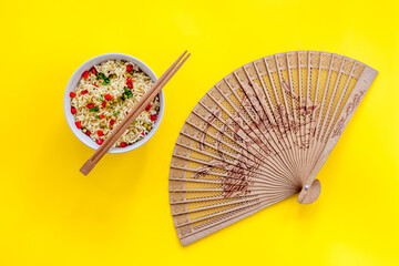 Instant noodle with pepper,peas, chopstick and tower. Yellow background top view copy space