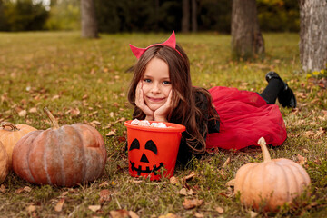 Happy devil with sweets celebrating Halloween in park