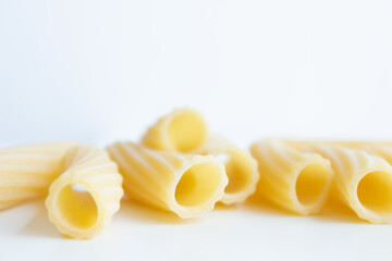 Bunch of raw macherroni pasta spread on white background, copy space