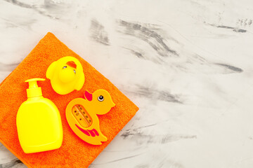 Obraz premium Bath cosmetics and Toy for child. Shampoo, gel, cream, soap and towel. Gray stone background top view