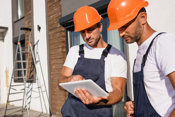 Selective focus of builders using digital tablet while working near house