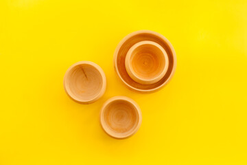 Obraz na płótnie Canvas Set of rustic wooden tableware - bowls and utensils on yellow background top view