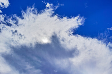 太陽が隠れた雲の広がる青空