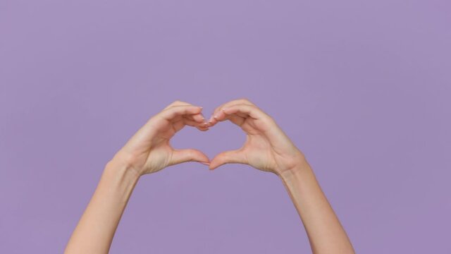 Close up cropped woman showing shape heart with hands heart-shape sign isolated on purple violet background in studio. Copy space place for text promotional content. Advertising area workspace mock up