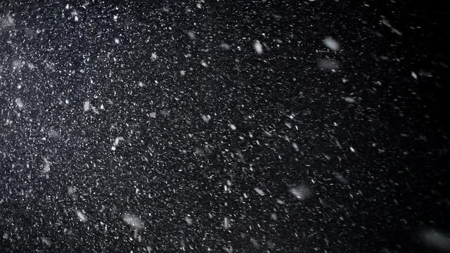 A dense blizzard snowstorm VFX insert in slow-motion on black screen. Black screen Christmas snowstorm. Particles swirling moved by wind. Snowstorm on black.