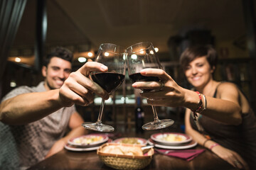 Couple having toast in restaurant with a glass of red wine