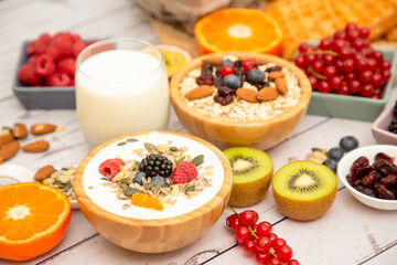 Breakfast Served in the morning with Butter bread and corn flakes Whole grains and raisins with milk in cups and Strawberry, Blueberry, Raspberry, Kiwi, Fresh Orange  on the breakfast table.