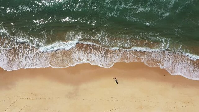 Overhead Aerial View of a man walking alone on an empty beach