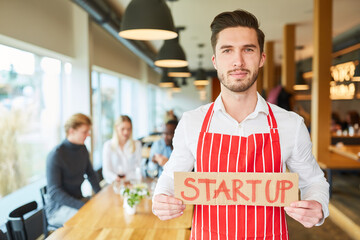 Junger Start-Up Gründer mit Schild im Restaurant