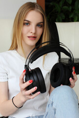 Fototapeta premium A young woman holds a pair wireless headphones in her hand.