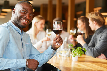 Mann mit einem Glas Rotwein sagt Prost