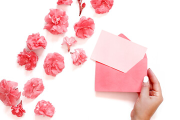 Hand keeps Pink envelope near pink flowers