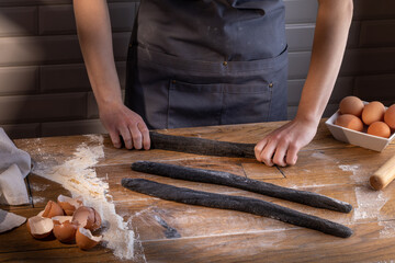 Chef preparing a portion of fresh dough with sepia addition for black dumplings. Cooking dumplings – step by step guide.