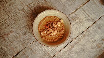 Chickpea stew with spanish prawns on wooden table in a restaurant
