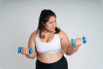 Fototapeta na wymiar Asian chubby woman in white sport bra exercise with blue dumbbells.