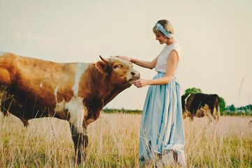 An elegant woman walking  alone in a farm with cows in the sunset