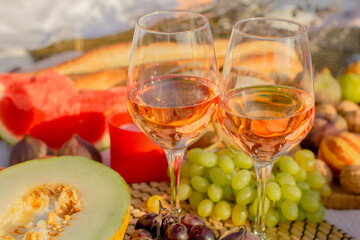 A picnic at dawn in gentle colors. Hot tea, fresh croissants, jam and fruit on a blanket with a wooden stand.
