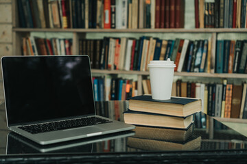 there is a laptop, a mug of coffee and books on the table in a cafe