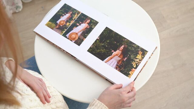 view top. pregnant woman flips through photo book from family pregnancy photo shoot.