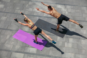 Youth. Young couple in sports outfit doing morning workout outdoors. Man and woman doing cardio and strenght exercises, practicing activity for lower and upper body. Sport, healthy lifestyle concept.