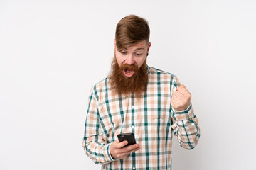 Redhead man with long beard over isolated white background surprised and sending a message