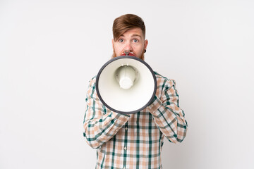Redhead man with long beard over isolated white background shouting through a megaphone