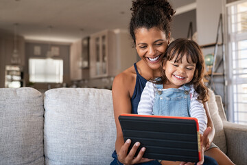 African smiling mother and happy daughter using digital tablet