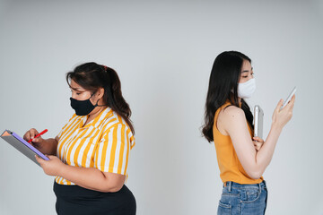 Asian business women wear mask working on file and smartphone.